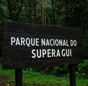 Parque Nacional do Superagui, tem placa de madeira com o nome do parque escrito, ao fundo uma floresta