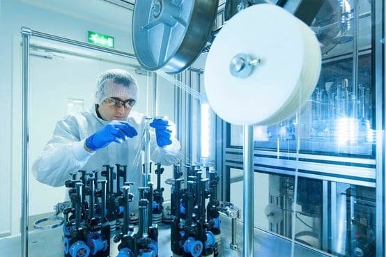 Cientista ou técnico em bioengenharia que esta trabalhando num equipamento com vários tubos cilíndricos no laboratório.