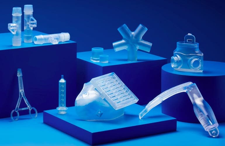 Vários objetos transparentes e brilhantes que se assemelham a materiais biocompatíveis. Todos os objetos estão em cima de uma mesa azul escura.