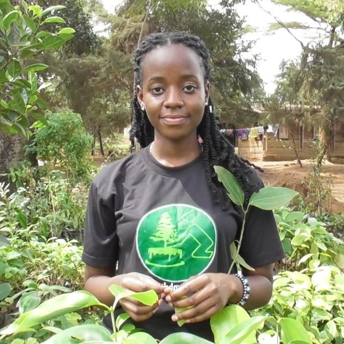Leah Namugerwa posa em uma horta graciosamente segundo um simbolo verde da sustentabilidade