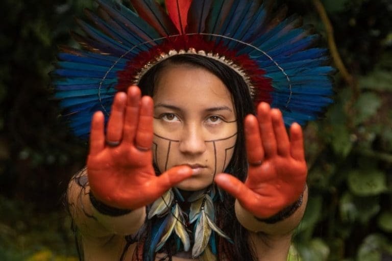 Samela Sateré Mawé com as mãos pintadas de vermelho em sinal de pare, protesta em favor da Amazônia