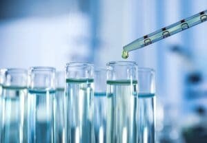 Tubos de ensaio alinhados e outro com conta gotas derramando um líquido produzido pela nanobiotecnologia