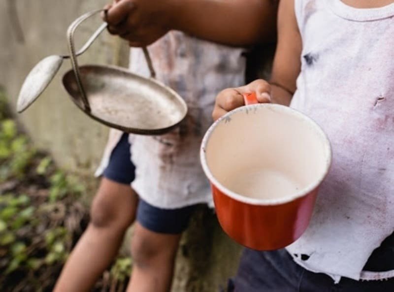 Criança mostra a panela vazia evidenciando a exclusão alimentar