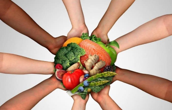 Mãos de pessoas de diversas culturas seguram alimentos em sinal da soberania alimentar