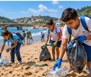 Estudantes de luvas recolhem garrafas e sacolas plásticas da areia numa praia, com um rio chegando ao mar ao fundo