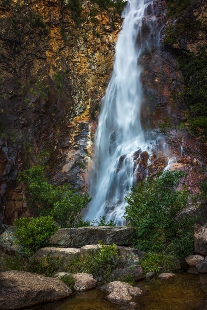 Cachoeira descendo um paredão de rocha entre a vegetação, no Parque Estadual Serra Nova e Talhado (MG)